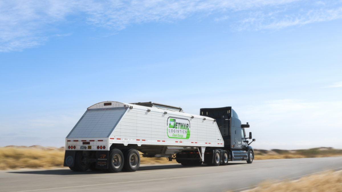 Detmar Logistics truck hauling sand trailer on open highway