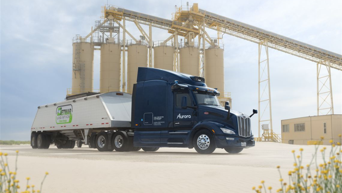 Autonomous sand hauler truck parked near industrial silos in Permian setting