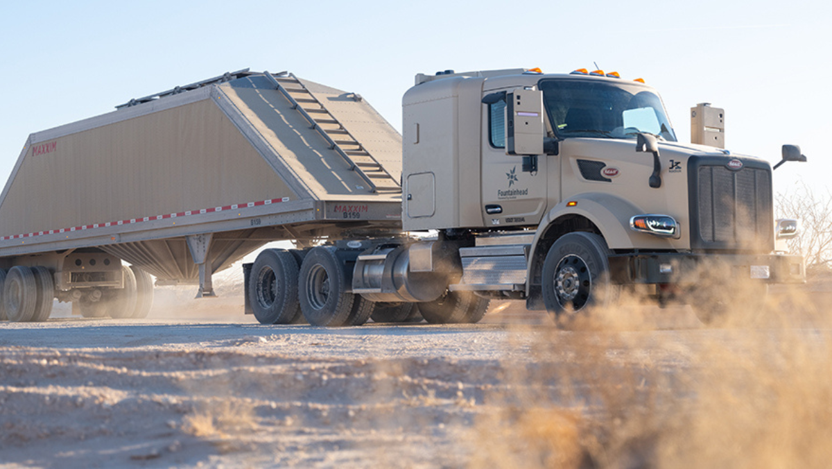 Autonomous heavy-duty truck hauling frac sand across a dusty Permian Basin road