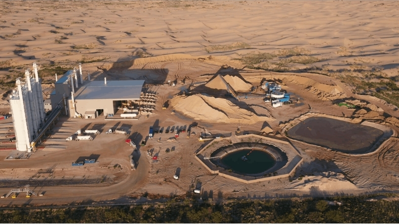 Aerial view of a dry frac sand facility with storage piles, silos, and loadout areas in West Texas