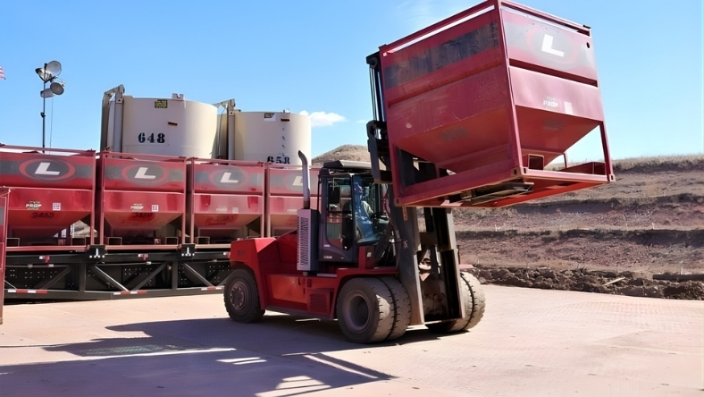 Forklift handling frac sand container at shale logistics yard